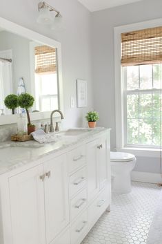 a bathroom with white cabinets and marble counter tops