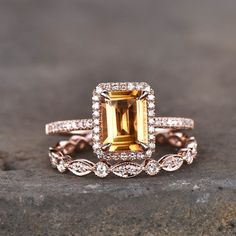 an engagement ring with a large yellow sapphire surrounded by smaller white diamonds on top of a rock