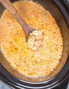 a wooden spoon in a slow cooker filled with soup