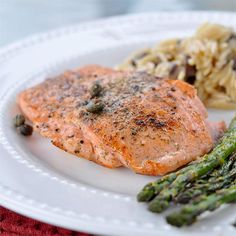 a white plate topped with salmon and asparagus