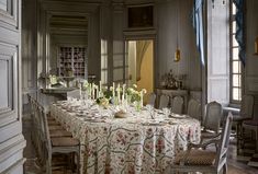 a dining room table is set with candles and flowers