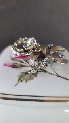 This is a beautiful vintage silver tone metal and blue aurora borealis crystal rhinestone floral brooch. Unsigned. A few light surface scratches and some minor discoloration consistent with age. Please see photos. Sold as is. Priced accordingly. Will be packaged in a gift box perfect for giving. I will refund any shipping overages. Does not include any props in photos. Please feel free to contact me with any questions you may have. Before you buy, please note that the items in my shop are pre-ow Silver Flower-shaped Brooches With Rhinestones, Blue Aurora, Sand Dollar Pendant, Blue Aurora Borealis, Floral Pendant Necklace, Aurora Borealis Crystal, Floral Brooch, Rhinestone Flower, Milwaukee Wi