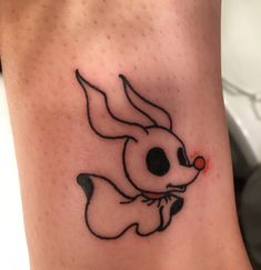 a tattoo on the leg of a person with a rabbit head and red dot in it