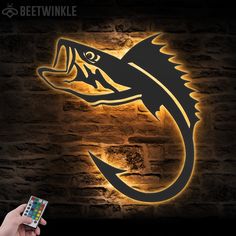 a person holding a remote control in front of a wall with a fish logo on it