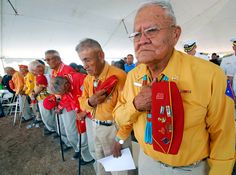 an old man standing in front of a row of other men holding red and yellow ribbons