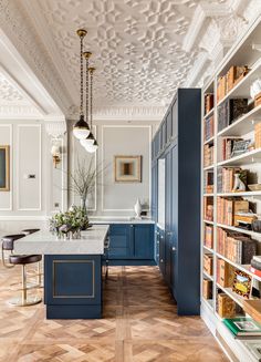 a kitchen with blue cabinets and an island in front of bookshelves filled with books