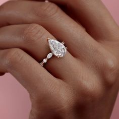 a woman's hand holding an engagement ring with two pear shaped diamonds on it