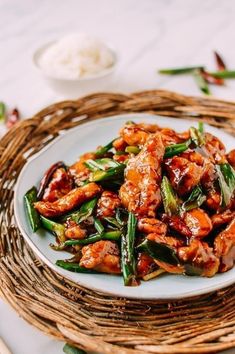 a white plate topped with chicken and green beans on top of a wicker place mat