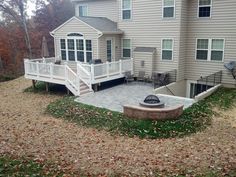 a house with a deck and fire pit in the front yard on a fall day