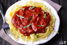 a plate of spaghetti with sauce and parmesan cheese on the side next to a fork