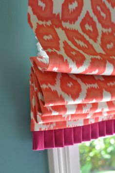 an orange and white patterned roman blind in front of a window