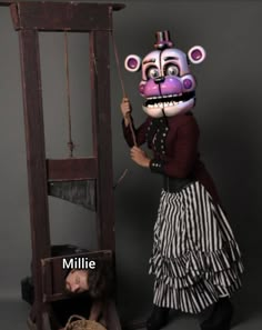 a person in a costume standing next to a creepy looking object with the caption millie on it