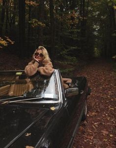 a woman sitting in the back of a black car