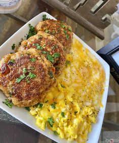 two crab cakes and scrambled eggs on a plate