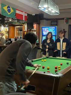 a group of people standing around a pool table