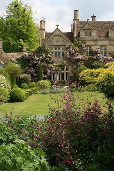 a large house surrounded by lush green trees and flowers