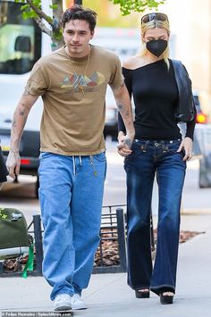 a man and woman walking down the street with masks on their faces as they hold hands