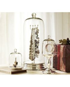 an assortment of jewelry is under a glass clochele on a table next to a gift box