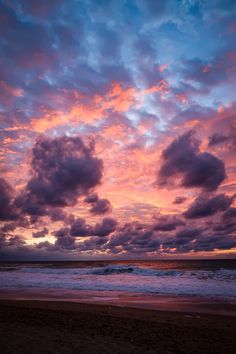 the sun is setting over the ocean and clouds