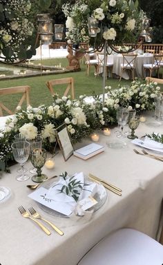 the table is set with white flowers and greenery