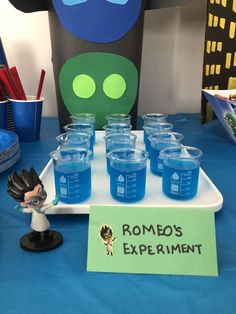 a table topped with glasses and mickey mouse figurines next to a sign that says, roma's experiment