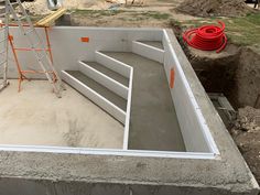 an unfinished pool being built in the middle of a construction site with ladders on each side