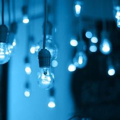 several light bulbs hanging from a ceiling in a room with blue lights on the walls