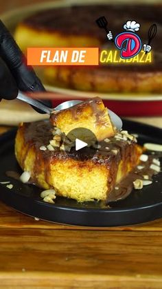 a person cutting into a piece of cake on top of a black plate with a knife