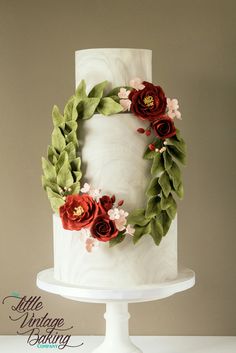 a white cake with red flowers and green leaves