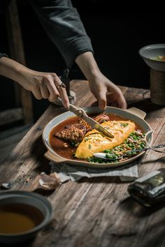 a person cutting food on top of a wooden table