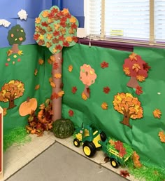 a classroom wall decorated with fall leaves and paper cutouts on the tree, tractor or farm scene