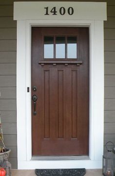 a brown front door with two pumpkins sitting on the ground in front of it