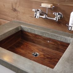 a sink made out of concrete and wood with a faucet on the side