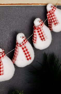 three snowmen are hanging on a line with red and white checkered scarfs