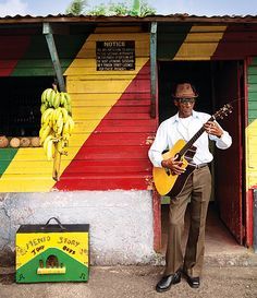 a man standing in front of a building holding a guitar