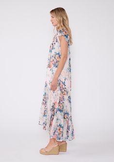 Our ultra-relaxed bohemian maxi dress is designed in a beautiful pink and blue floral print and features short flutter sleeves and flowy ruffle-trimmed high-low skirt. Dress it up with a a cute wedge for your next special occasion, or pair it with easy boho flat sandals for a relaxed spring/summer outfit. Floral print Chiffon Relaxed fit Short flutter sleeves High-low skirt Adjustable tie cuffs Maxi length Ruffle-trimmed tiered skirt Round neckline with tassel ties Button front Contrast bib Shee Summer Floral Print High-low Hem Dress, Summer Floral Print Dress With High-low Hem, Flowy Short Sleeve Maxi Dress In Breezy Style, Flowy Breezy Short Sleeve Maxi Dress, Breezy Flowy Maxi Dress With Short Sleeves, Flowy Breezy Maxi Dress With Short Sleeves, Summer Beach Maxi Dress With Flutter Sleeves, Beach Midi Dress With Flowy Skirt And Short Sleeves, Casual Ruffle Sleeve Maxi Dress For Garden Party