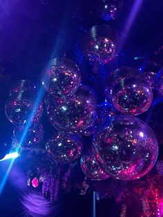 several disco balls in the middle of a room with purple lights on them and one person standing next to it