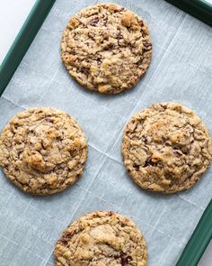 four chocolate chip cookies sitting on top of a piece of parchment paper