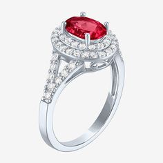 a ring with a large red stone surrounded by white diamonds on the sides and an oval shaped