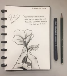 a notepad with a drawing of a hand holding a flower next to a pencil