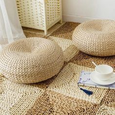 two wicker bean bags sitting on the floor next to a cup and saucer