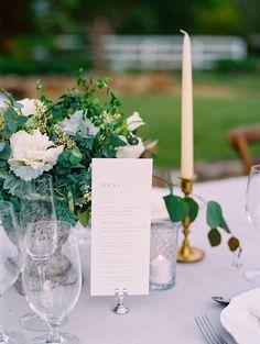 the table is set with flowers, candles and menu cards for guests to sign in