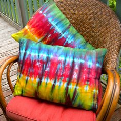 two colorful pillows sitting on top of a chair