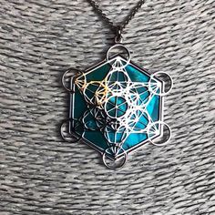 "Metatron in 925 silver and acquamarine mother of pearl backdrop. The cube known as Metatron takes name by the same Archangel, known as God's scribe. It contains every shape that exists in the universe God has created combining male and female aspects. Within the cube thirteen spheres of female eneregy lies drawing the Fruit of Life, in the middle of which male straight lines are irradiated. In its shapes a triangle and two cubes are also created by six line started from the middle. It also cont Handmade Silver Geometric Jewelry, Geometric Silver Necklace For Gift, Silver Geometric Necklace For Gift, Blue Geometric Jewelry As A Gift, Blue Geometric Jewelry For Gifts, Lies Drawing, Scared Geometry, Pearl Backdrop, Universe God