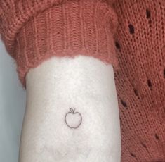 a small apple tattoo on the left inner arm