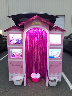 a pink play house with curtains and buckets on the ground in front of it