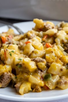 a white plate topped with macaroni and cheese next to a silver fork on top of a table