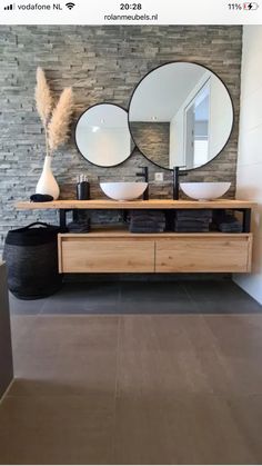 a bathroom with two sinks and three mirrors on the wall above it is also a large round mirror