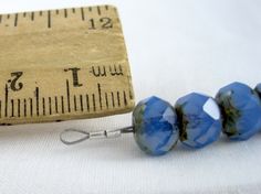 two blue beads sitting next to a ruler