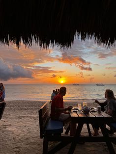 two people sitting at a picnic table on the beach